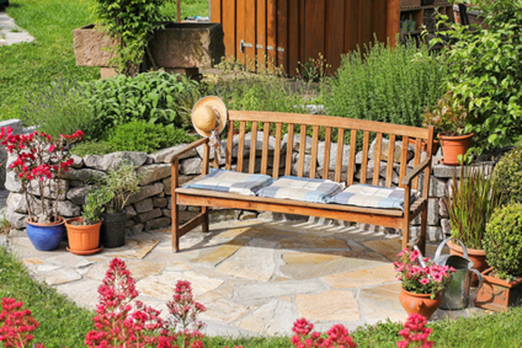 mediterraner Sitzplatz an Natursteinmauer mit Kräuterbeet